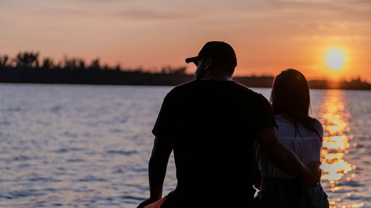 A man and woman sitting on a rock looking at the sunset, date night in Ontario